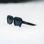 Stylish sunglasses rest on fresh snow, capturing a serene winter ambiance.